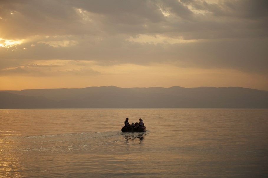 sunrise at the Dead Sea and team departing from shore to take samples by SCUBA diving.
