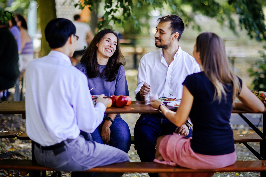 Four employees sit together during their break on the green UFZ campus. Photo: Anne Schwerin