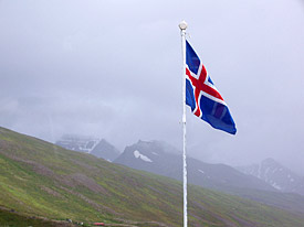 Isländische Fahne vor wolkenverhangenen Berg