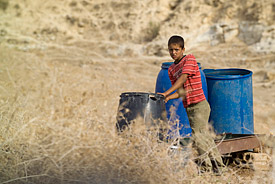 Für mehr als ein Drittel der Weltbevölkerung gehören Wasserknappheitsprobleme zu den größten Herausforderungen Junge mit Wasserbehältern im Nahen Osten